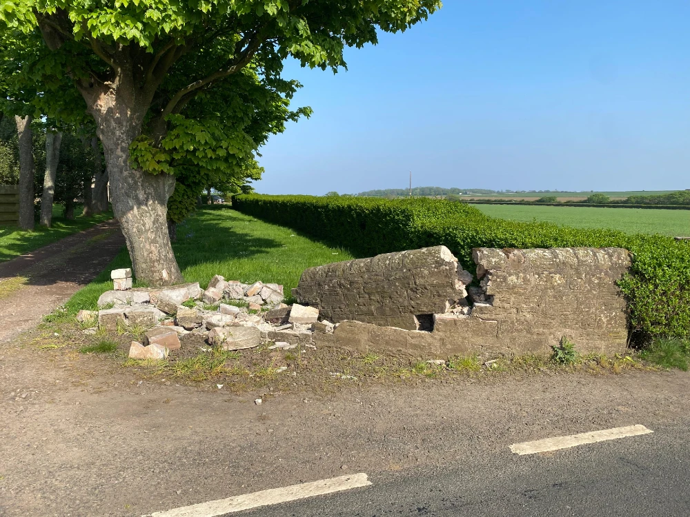 A garden wall that has been knocked over from a car crash incident